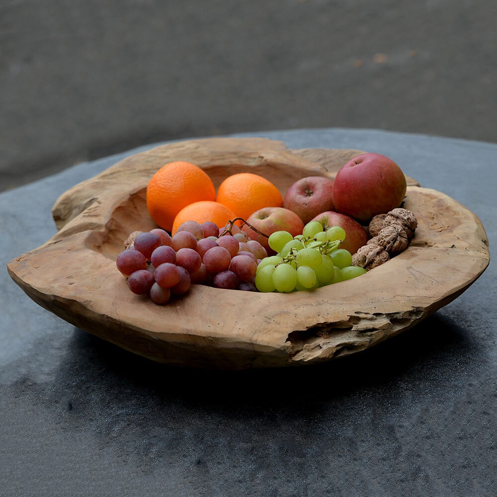 Handgefertigte rustikale Holzschale mit frischem Obst auf Gartentisch