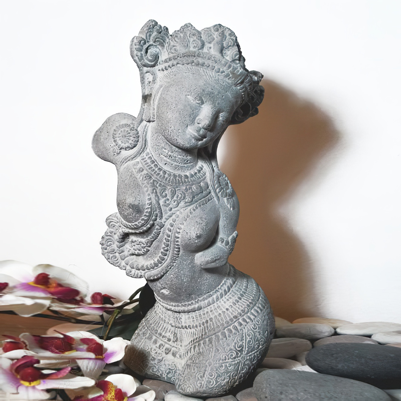 Figurine de femme orientale noire et ornée sur des pierres avec des fleurs