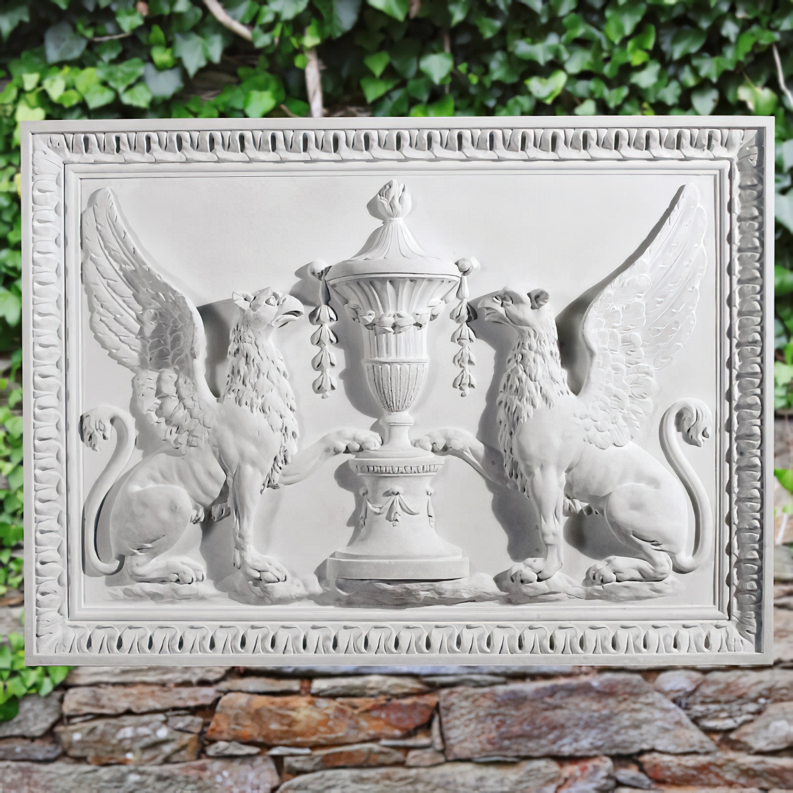 Bas-relief blanc en pierre montrant deux griffons de chaque côté d'un vase décoré, exposé dans un jardin