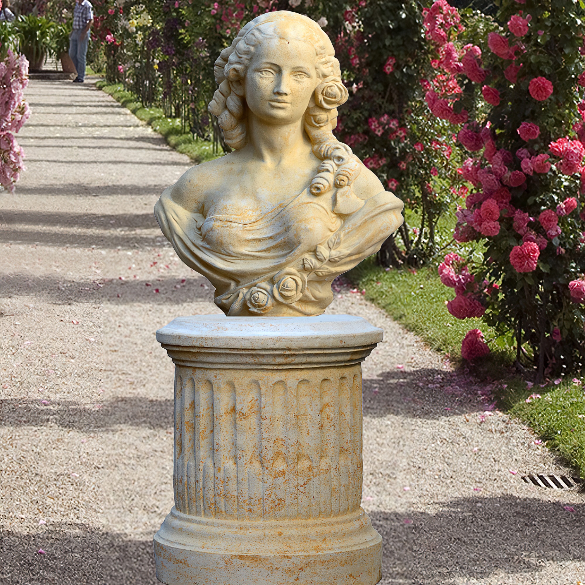 Busto in pietra di una donna su un piedistallo in un giardino con rose e un sentiero di ghiaia