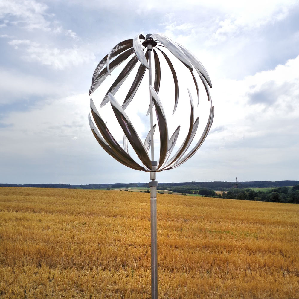 Scultura cinetica in acciaio inossidabile argento in un campo sotto un cielo nuvoloso