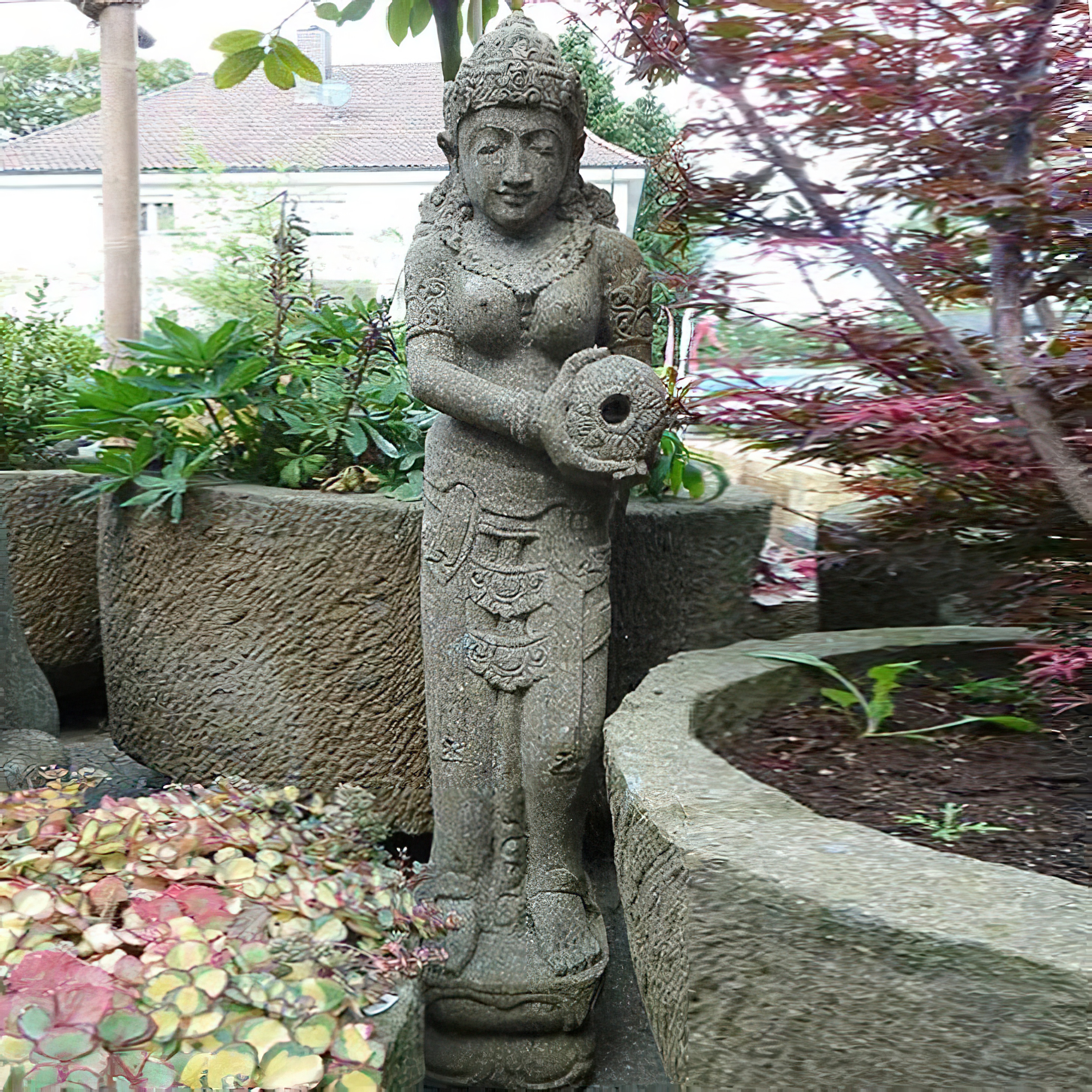 Gartendekoration mit steinerner Statue einer antiken weiblichen Figur zwischen Pflanzen