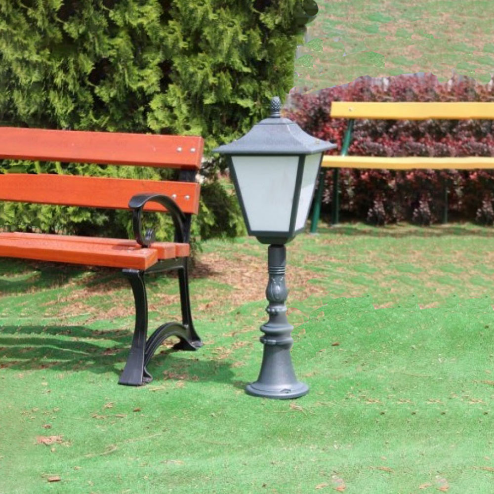 Schwarze Gartenlaterne zwischen einer roten und einer orangefarbenen Bank auf grünem Rasen