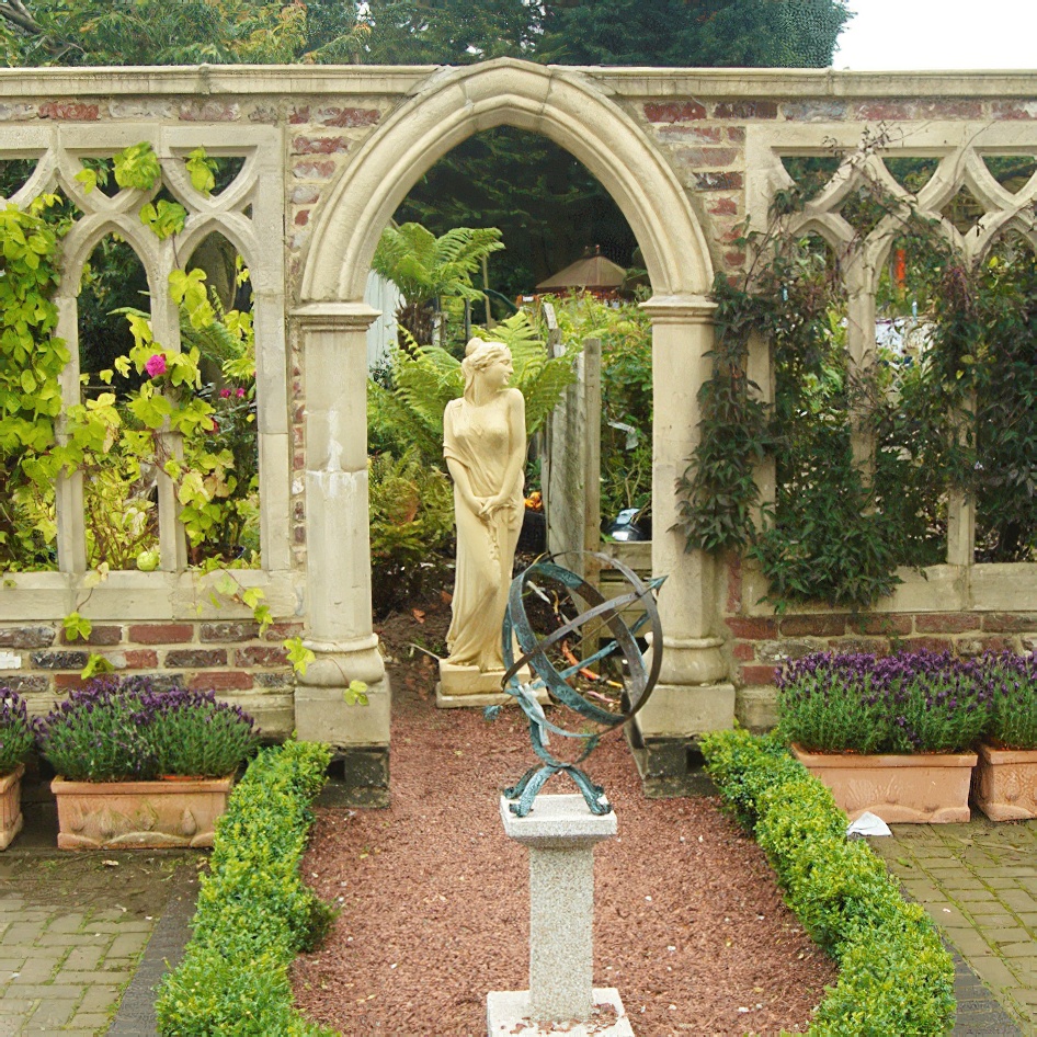 Giardino con meridiana decorativa su piedistallo e muro in pietra classico con arco