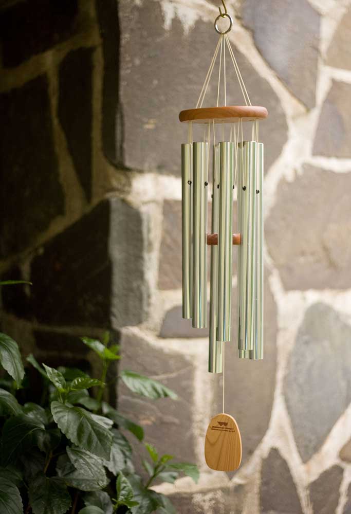 Carillon métallique avec des détails en bois suspendu devant un mur en pierre