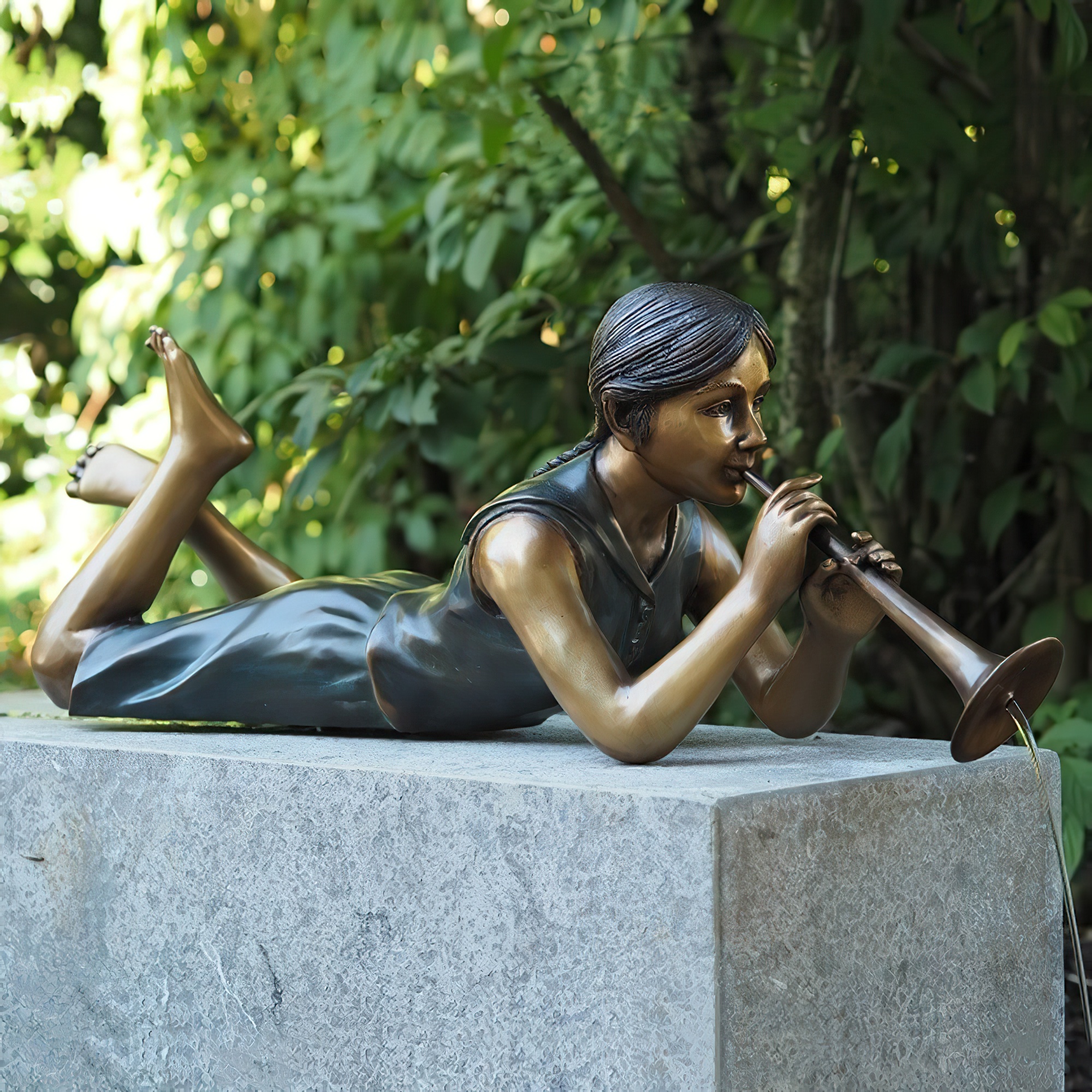 Sculpture en bronze d'une femme allongée jouant de la flûte sur un socle gris dans un jardin