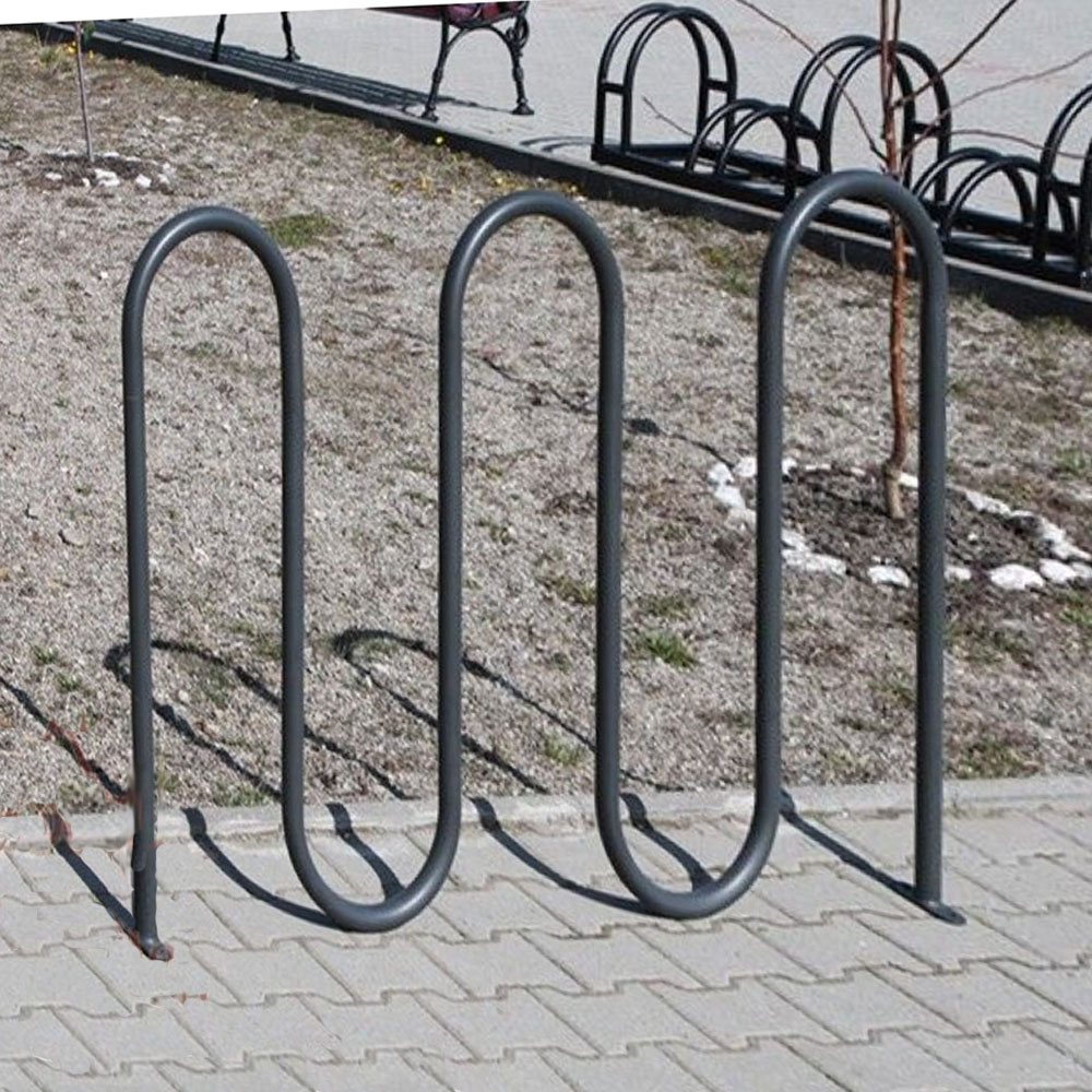 Robuster schwarzer Fahrradständer auf gepflastertem Boden neben einem Kiesgarten
