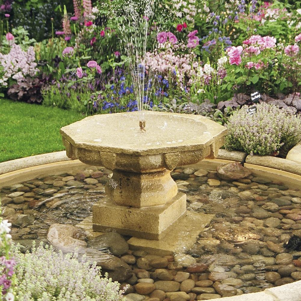 Bella fontana in pietra con acqua corrente in un giardino piantumato