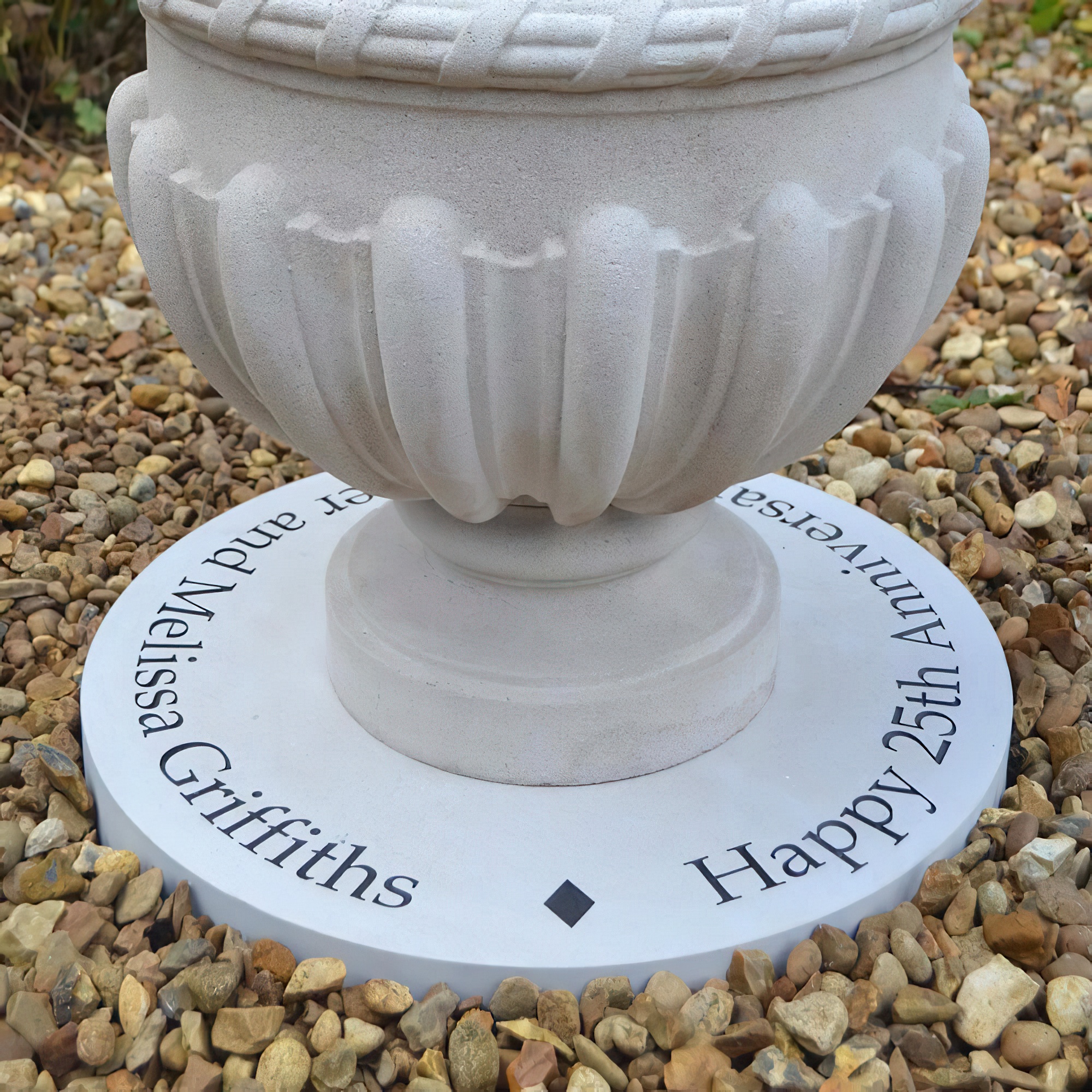 Fontaine de jardin blanche avec gravure personnalisée sur une plaque en pierre, entourée de cailloux