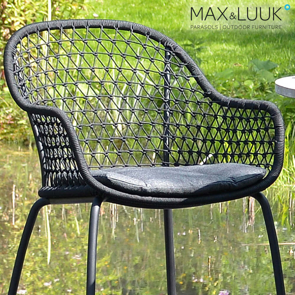 Schwarzer Geflecht-Gartenstuhl mit grauem Sitzkissen draußen auf der Wiese