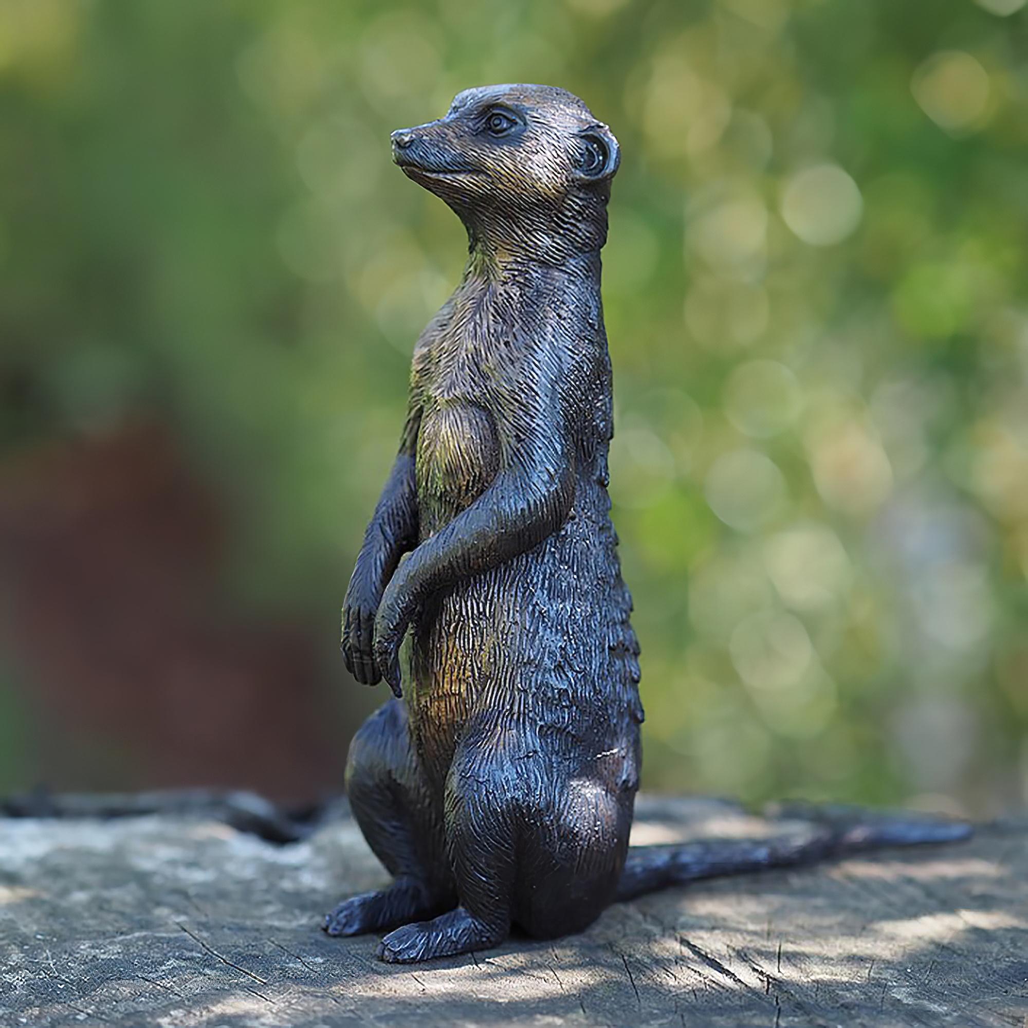 Sculpture détaillée d'un suricate en métal sur bois dans un jardin