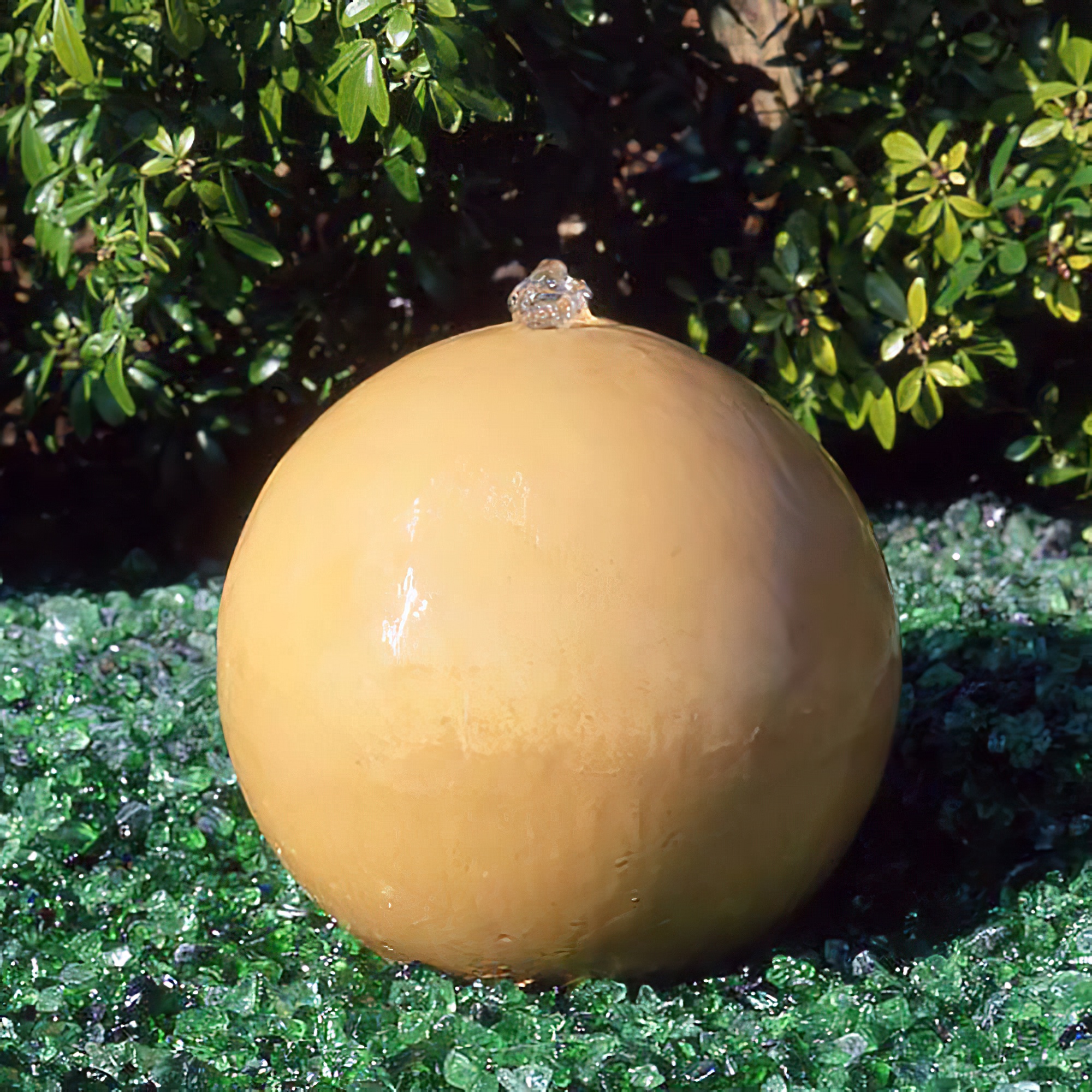 Beiger, kugelförmiger Gartenbrunnen im Grünen auf Glassteinen