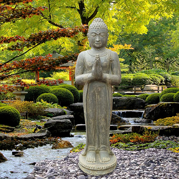 Statua di Buddha in pietra in un giardino con piante verdi e cascata sullo sfondo