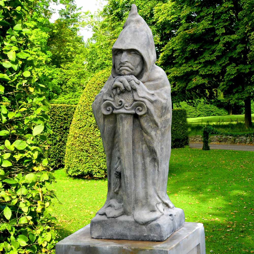 Statua in pietra di un cavaliere con elmo e spada in un giardino verde