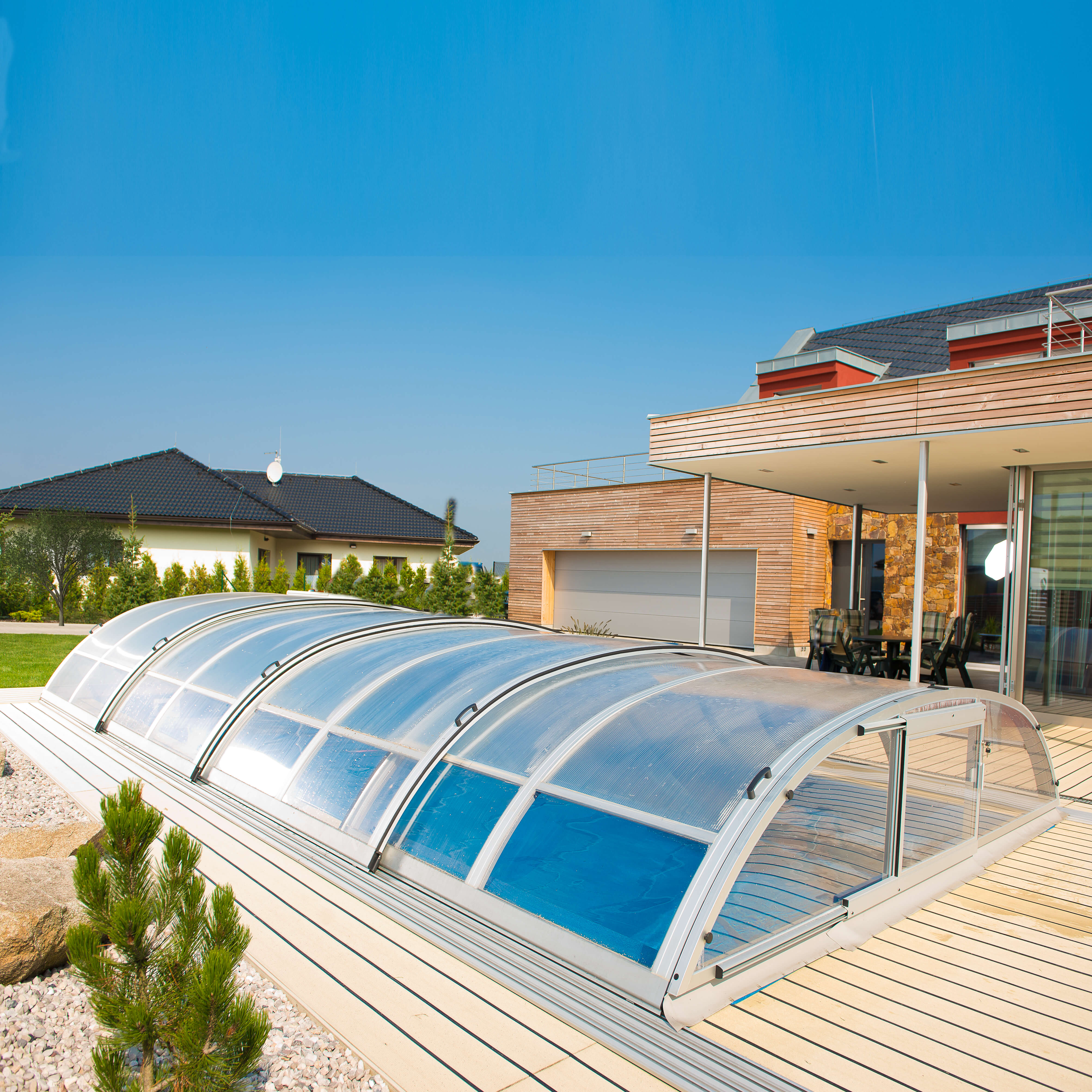 Giardino moderno con copertura trasparente per piscina davanti a una casa
