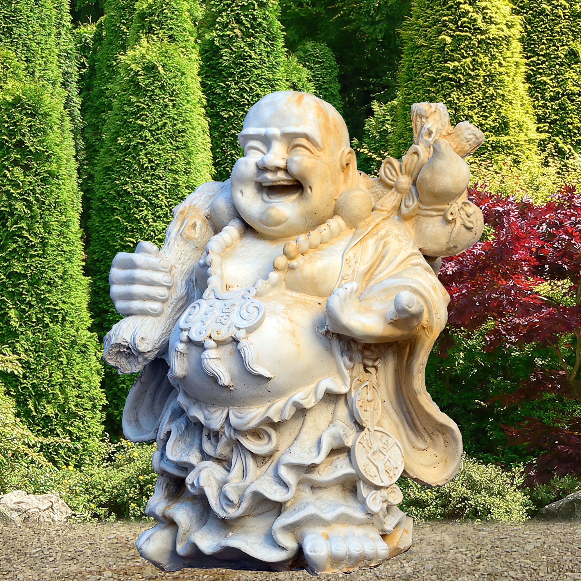 Große weiße Buddha-Skulptur in einem Garten vor grünen Büschen und roten Pflanzen