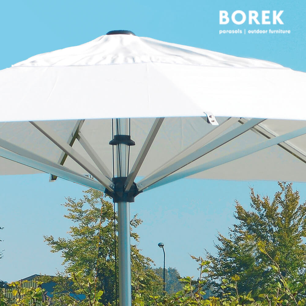 Weisser Gartenschirm im Freien vor blauem Himmel und Bäumen