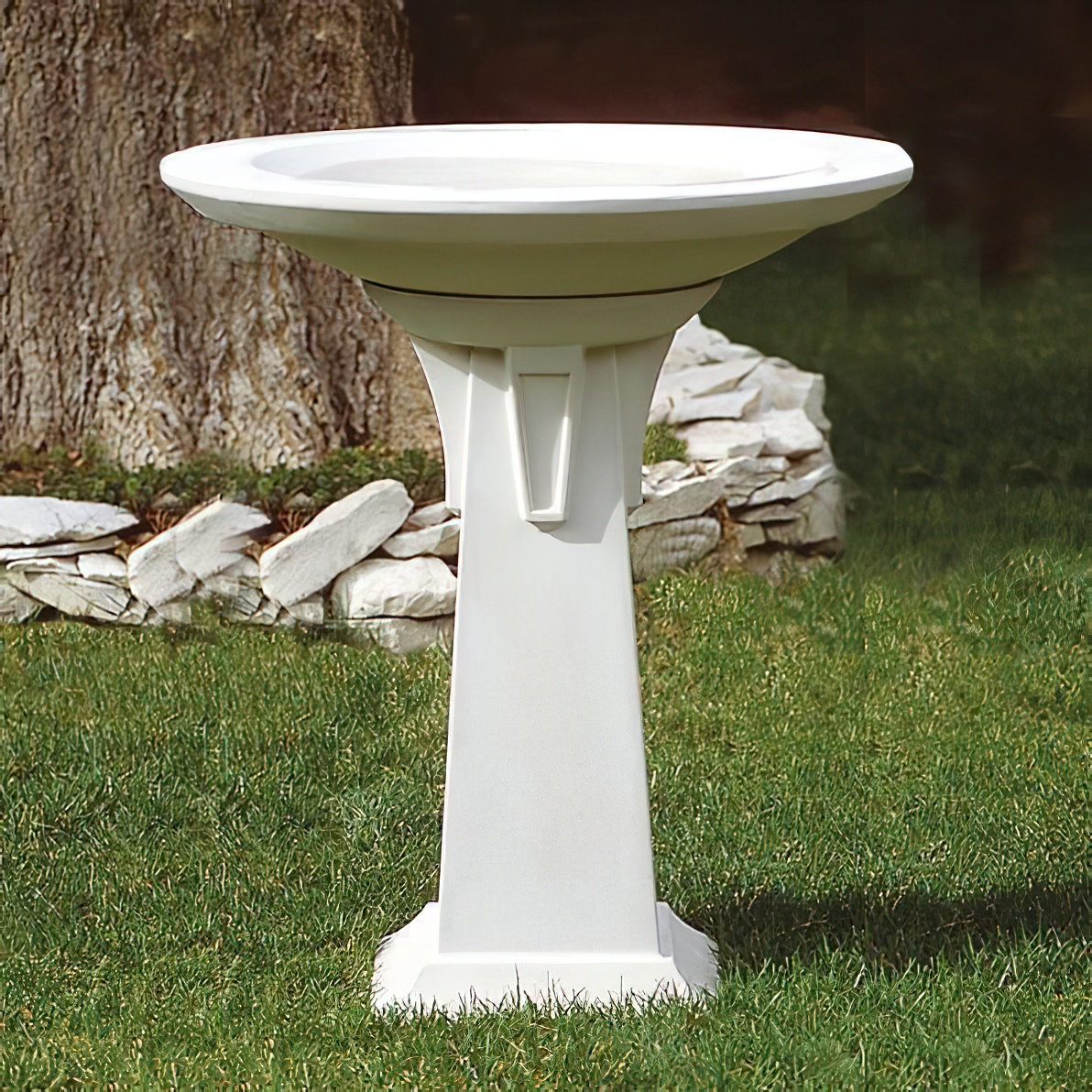 Abbeveratoio bianco moderno per uccelli in pietra in giardino su prato verde