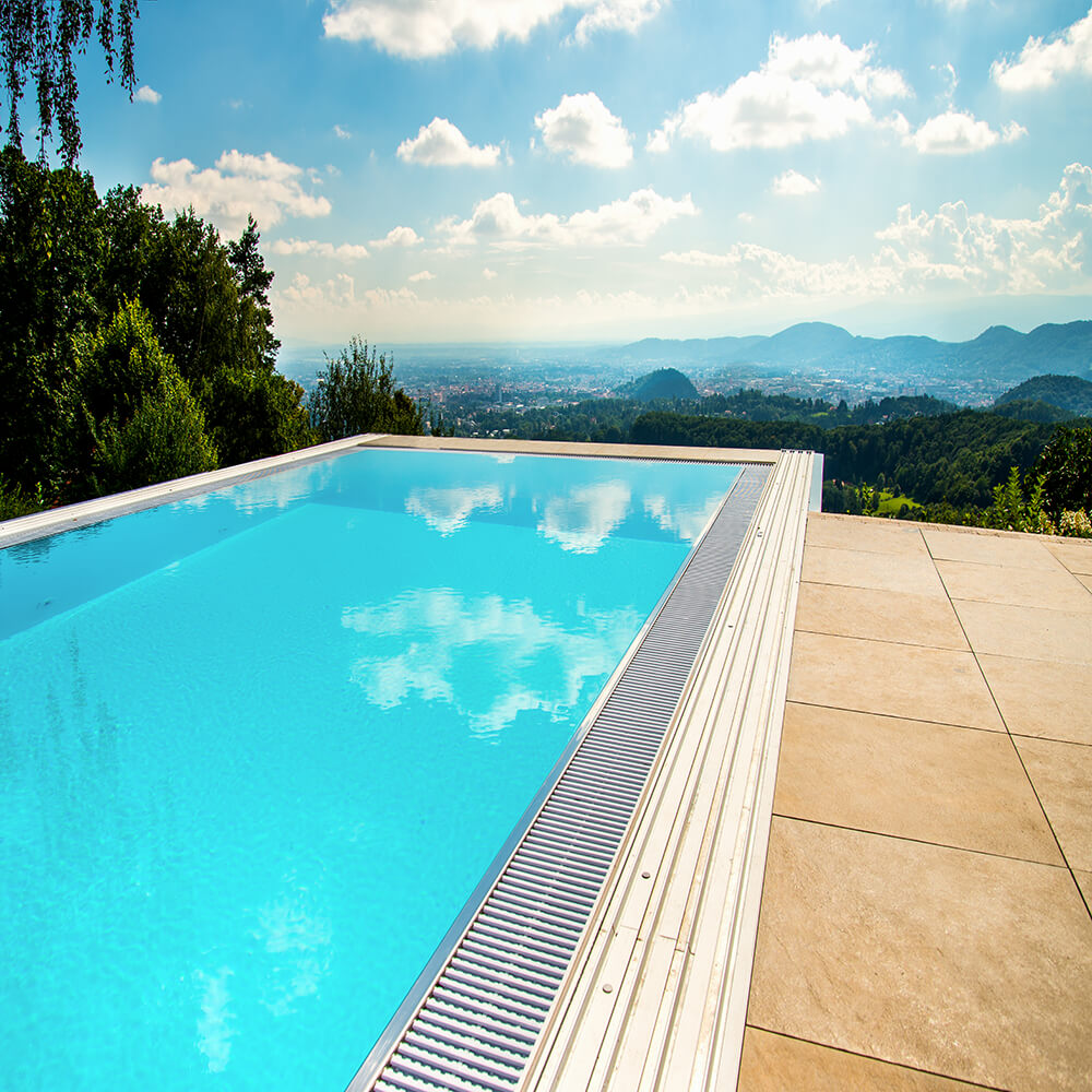 Piscina blu con riflesso del cielo, terrazza e montagne sullo sfondo