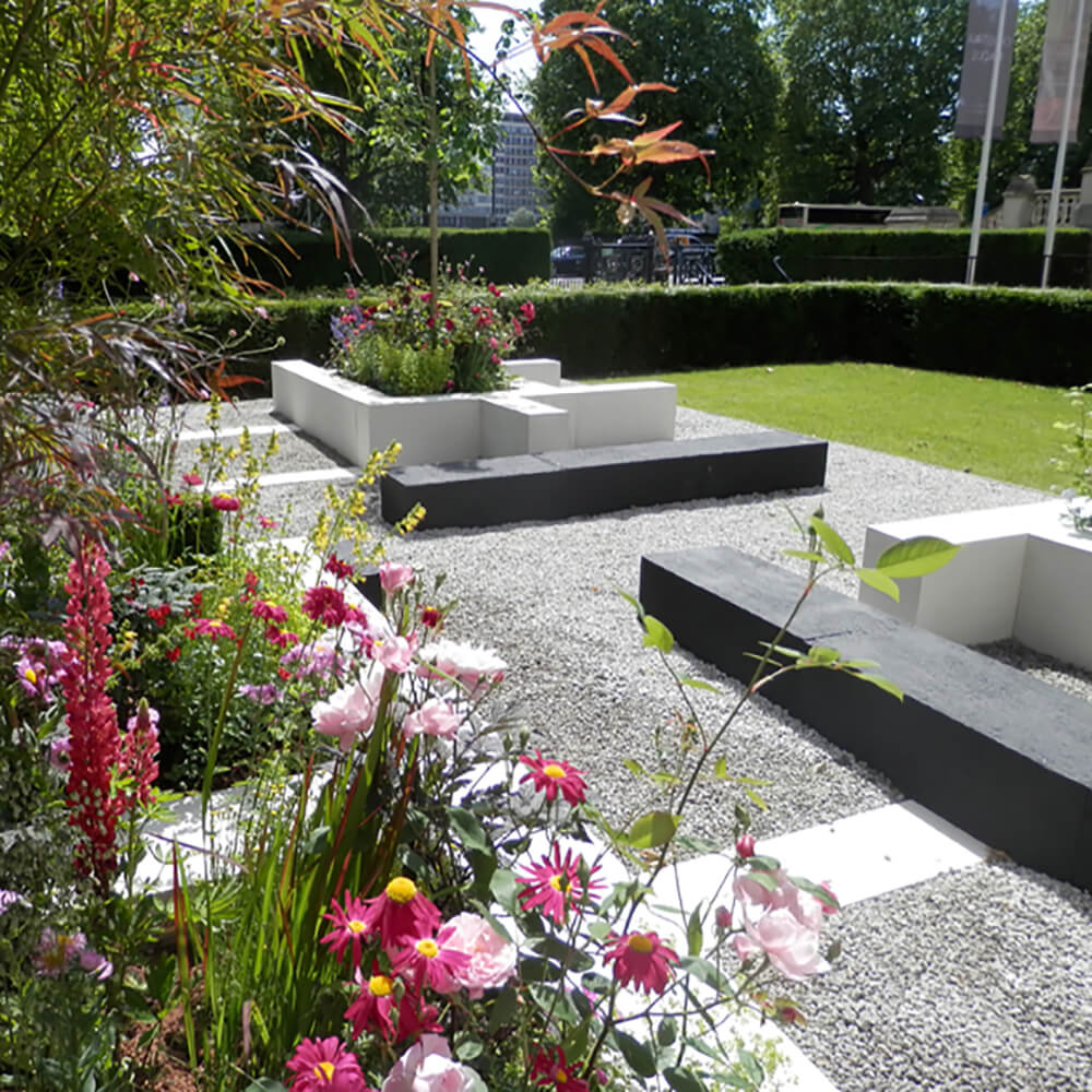 Weisser Garten mit Blumen und modernen Betonbänken in sonnigem Ambiente