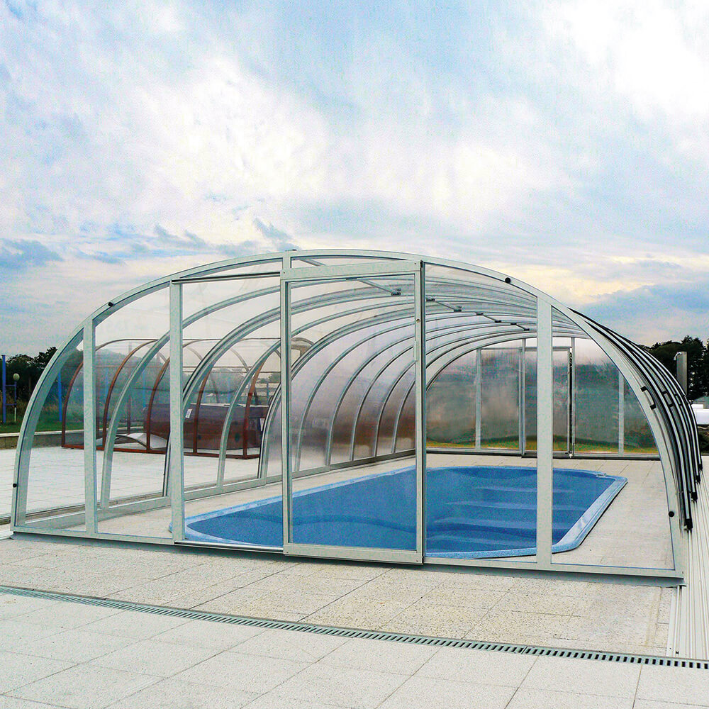 Abri de piscine incurvé transparent en verre et métal sur une piscine de jardin