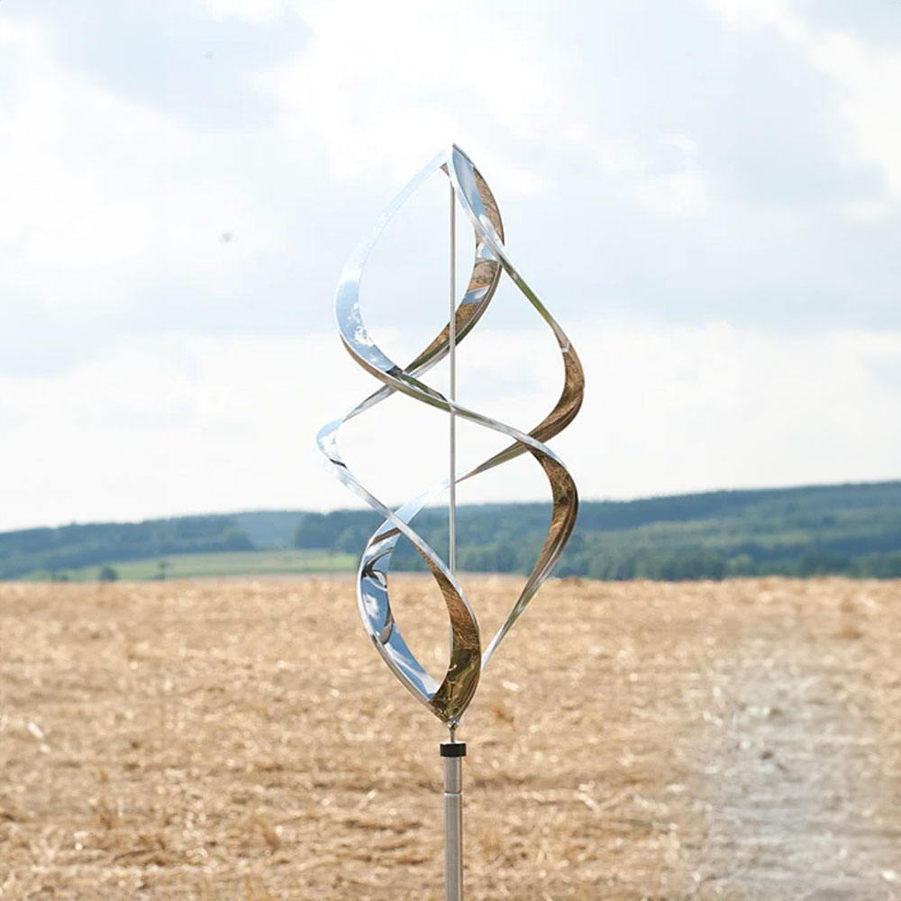 Decorazione da giardino girevole a spirale in metallo lucido davanti a un paesaggio di campi