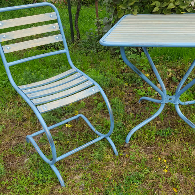 Blauer Gartenstuhl und passender Gartentisch auf Gras in Gartenumgebung