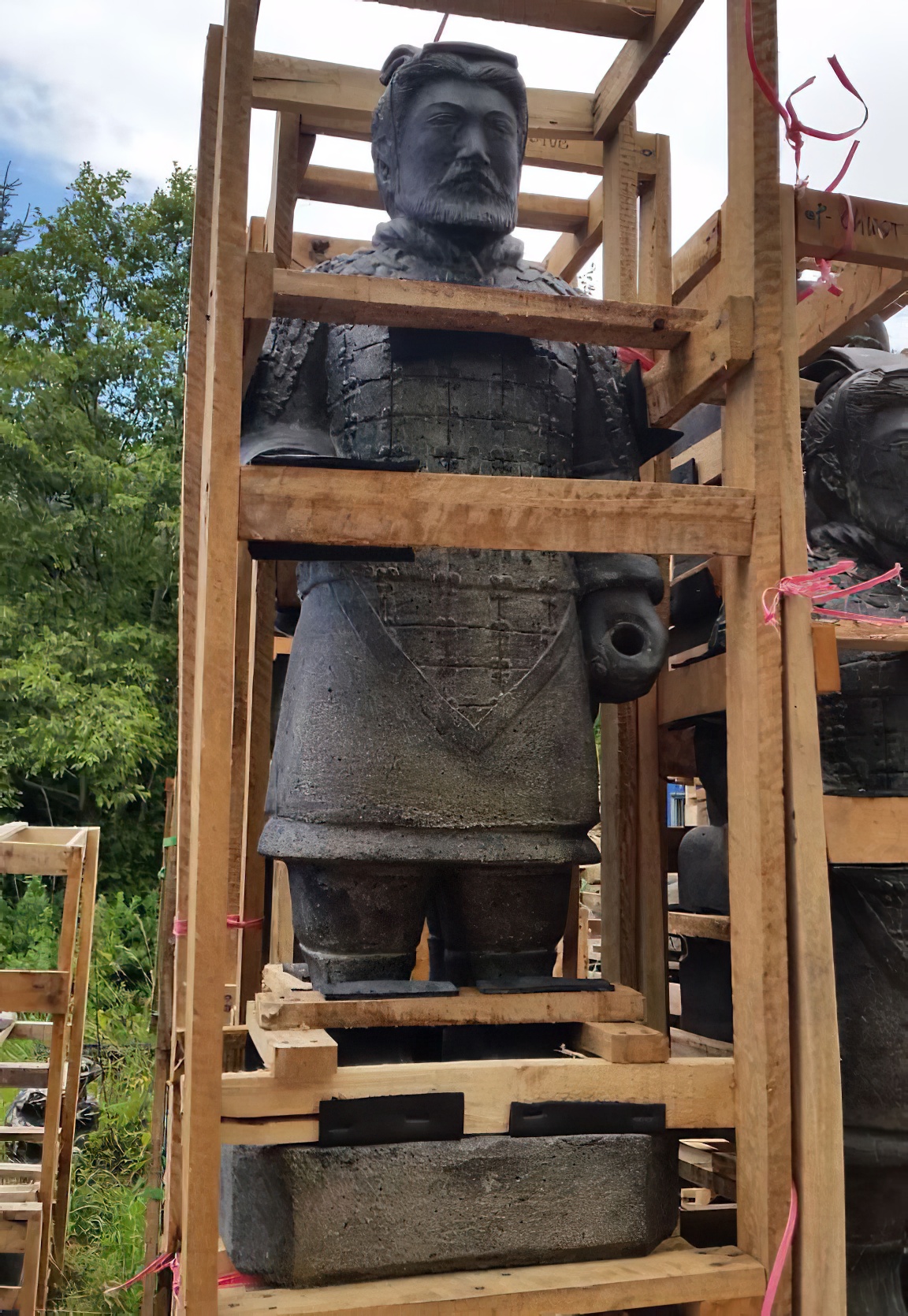 Grande scultura di guerriero in terracotta in una struttura di legno nel giardino