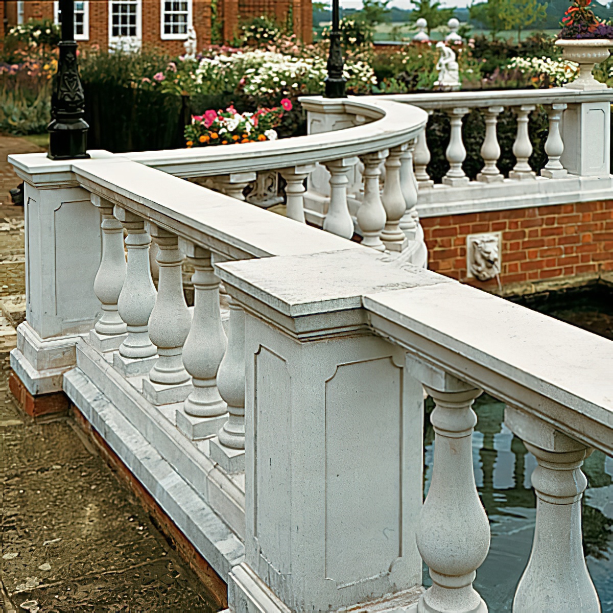 Weiße Steinbalustrade mit Säulen und Zierdetails im Garten vor Gebäude