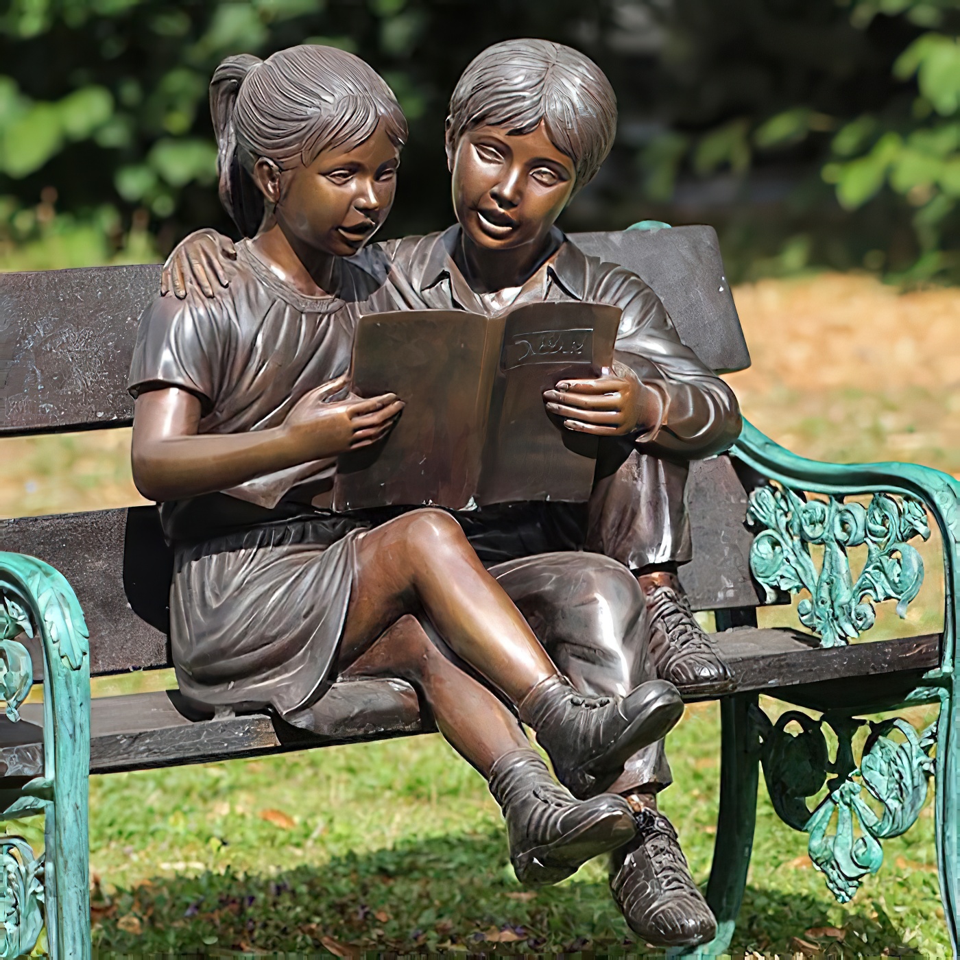 Statue en bronze de deux enfants lisant un livre ensemble sur un banc de jardin