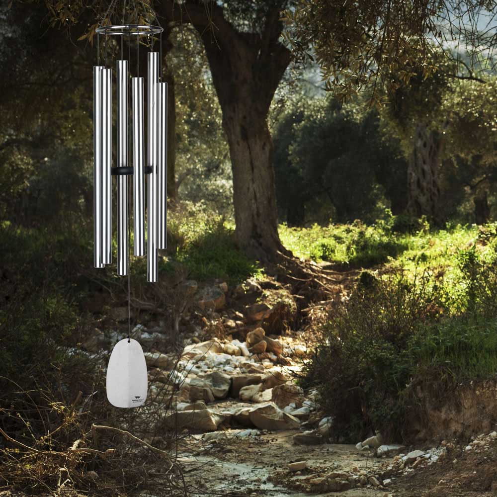 Carillon argenté suspendu à un arbre dans un jardin naturel