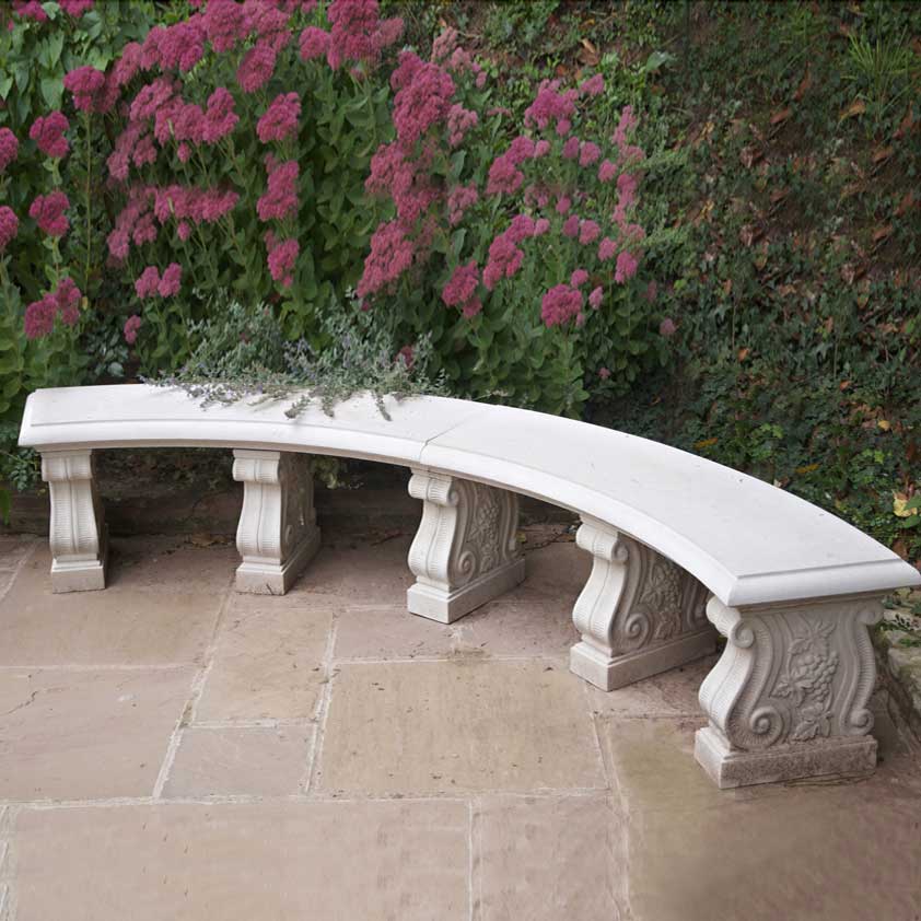Banc de jardin blanc incurvé devant un buisson rose en fleurs