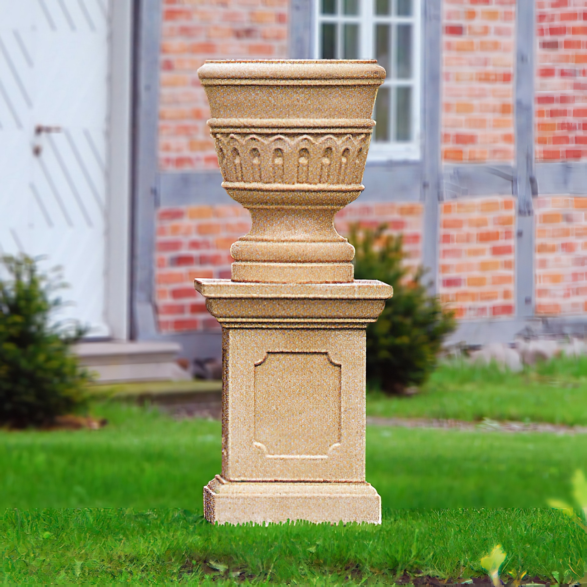 Grande fontaine colonne en pierre avec urne devant un mur en briques