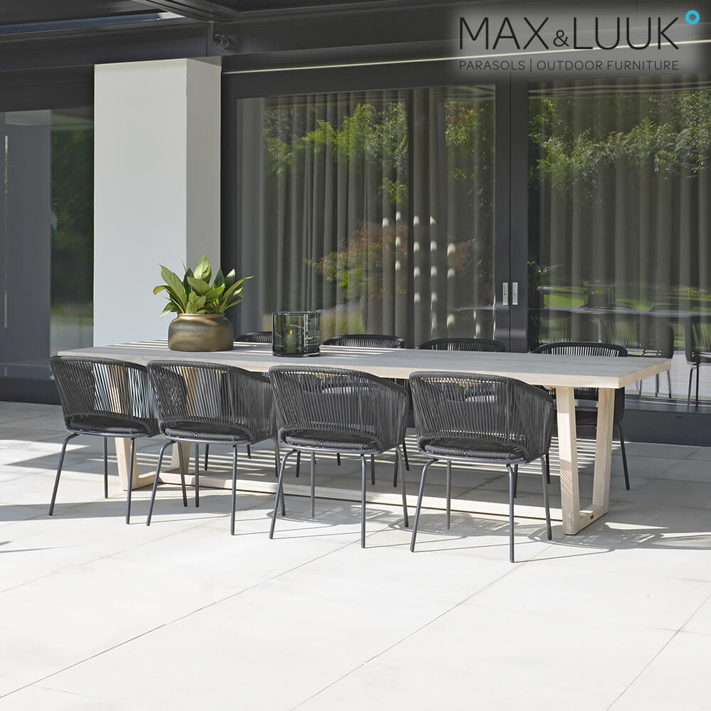 Grande table de jardin en bois avec six chaises noires sur une terrasse moderne