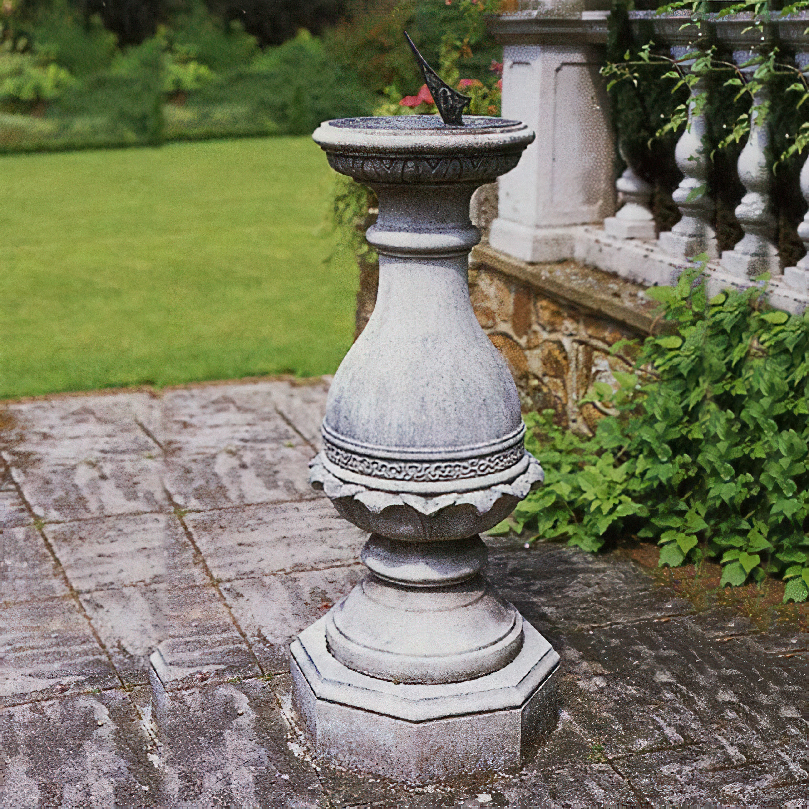Fontana da giardino in pietra bianca con decorazioni su una terrazza circondata da verde