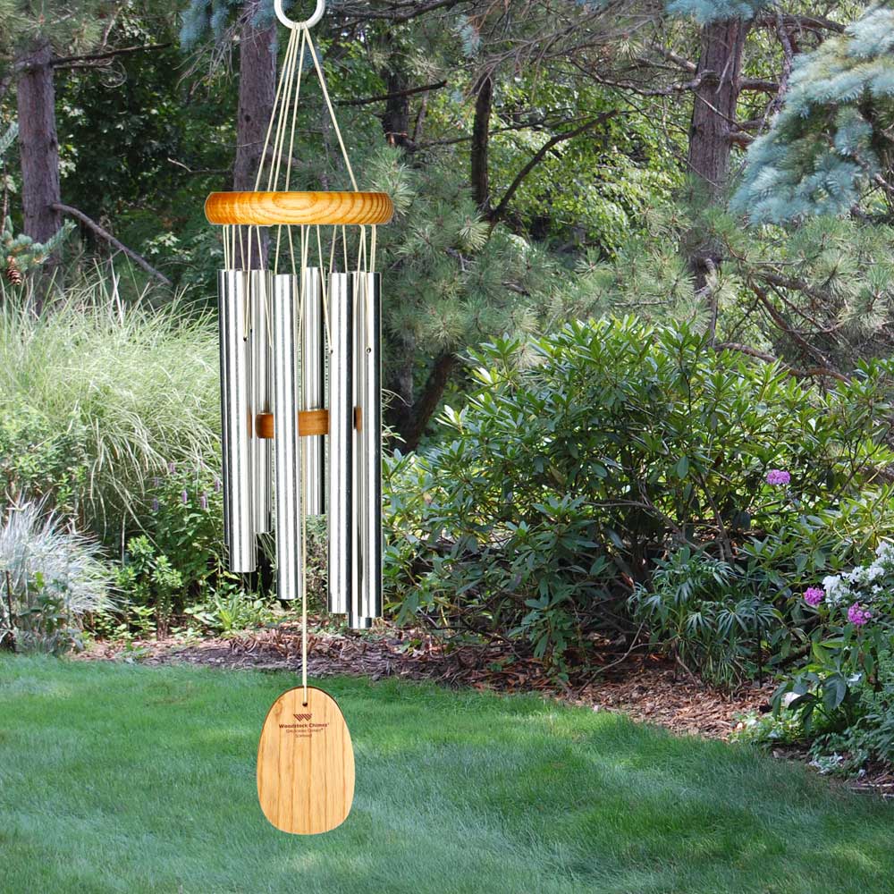 Carillon en métal argenté avec des détails en bois suspendu dans un jardin vert