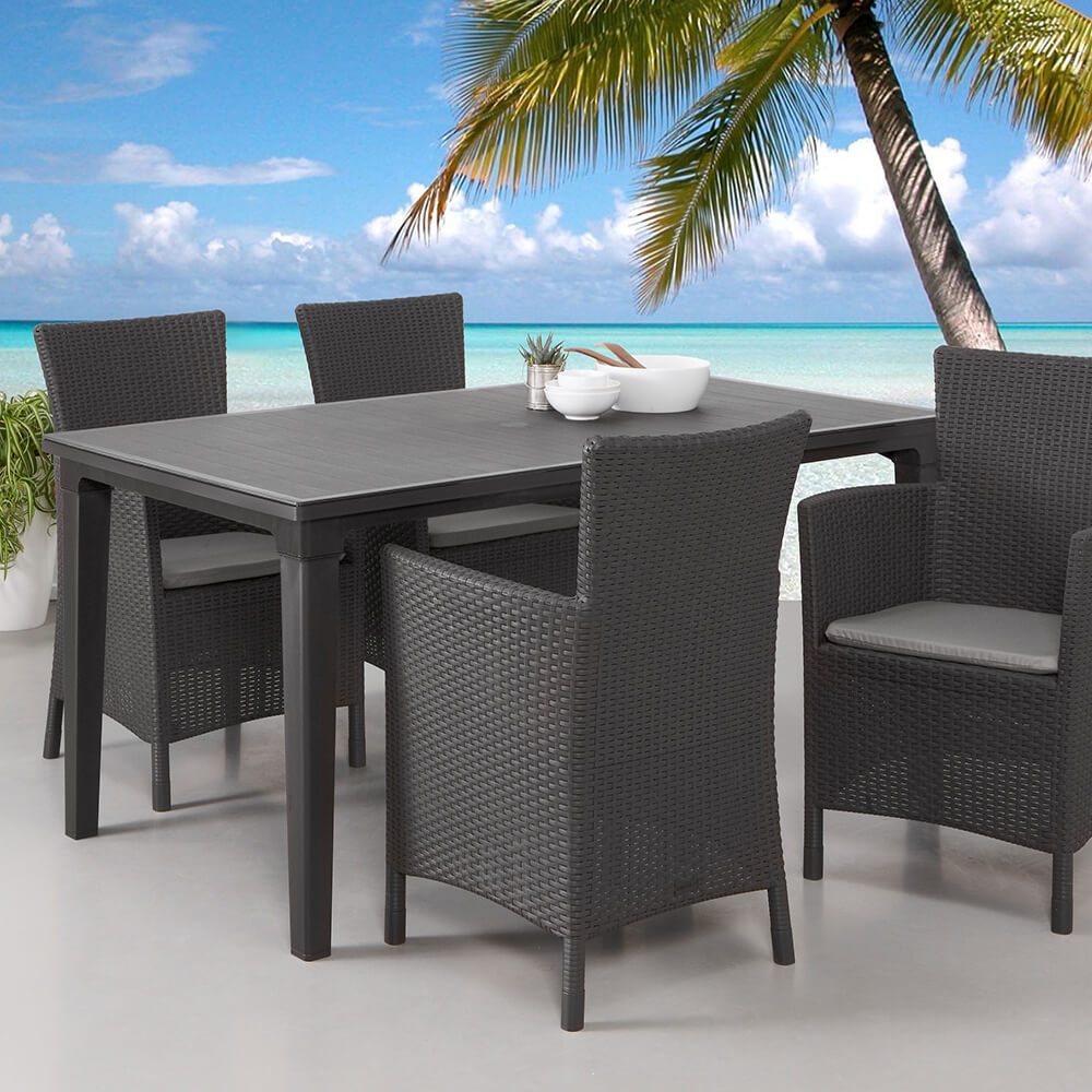Ensemble exclusif de mobilier de jardin en rotin avec table et quatre chaises sur une terrasse au bord de la mer avec des palmiers