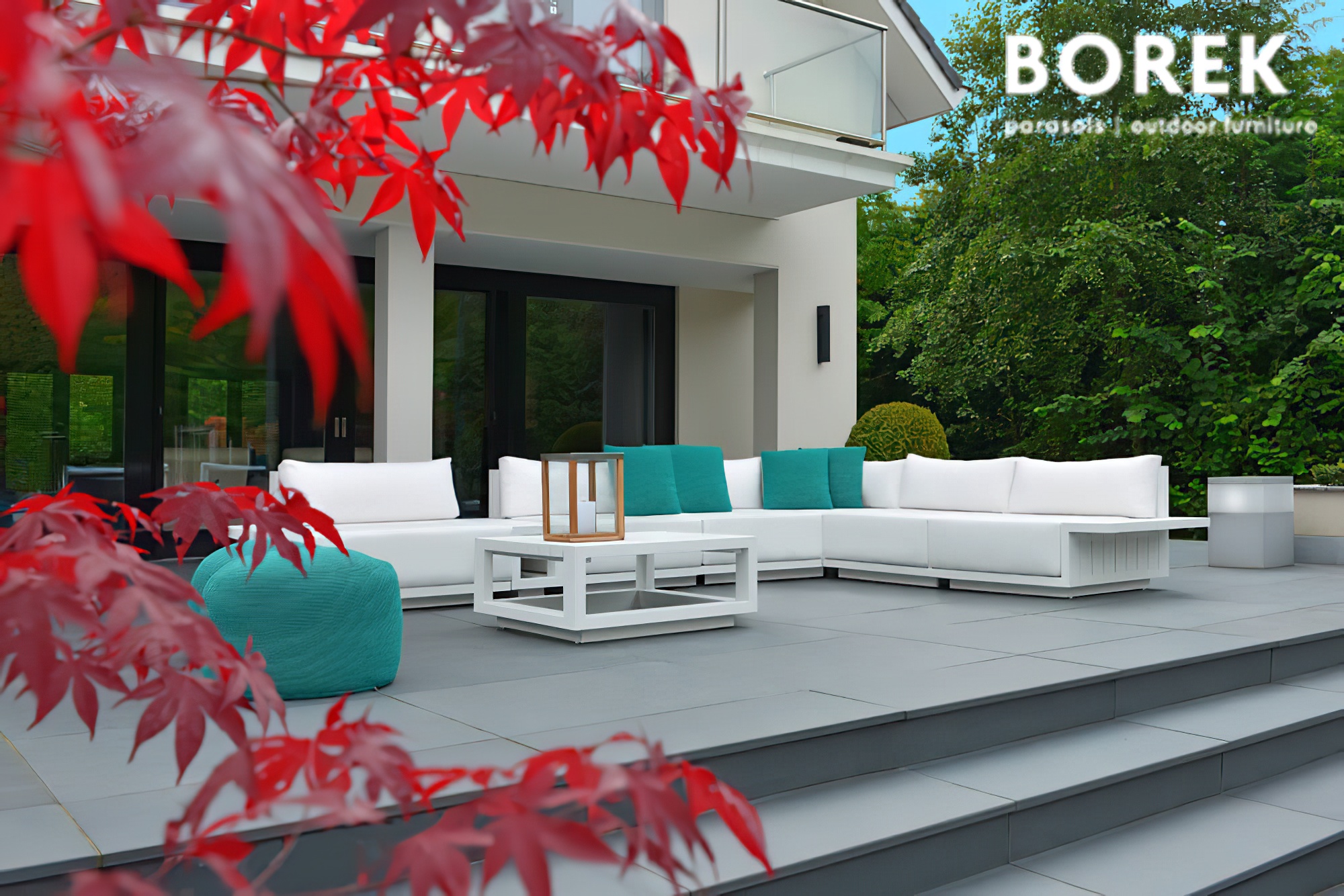 Mobilier de jardin blanc et turquoise sur une terrasse avec un érable rouge en premier plan