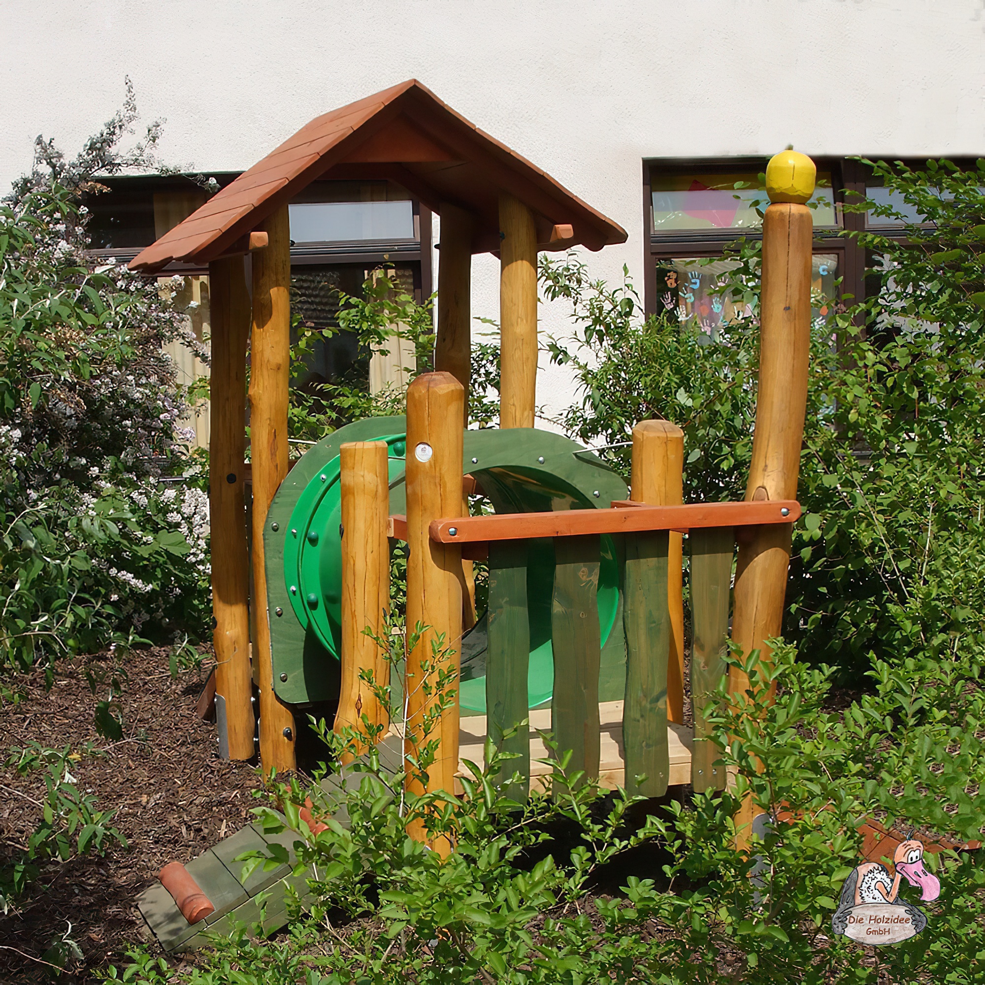 Holzspielplatz mit grünem Tunnel und Dach im Garten, umgeben von Pflanzen