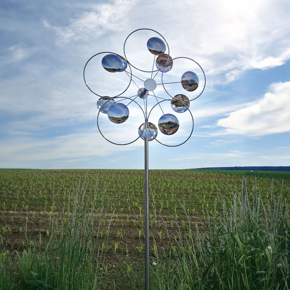 Mobile da giardino con sfere riflettenti davanti a un campo e cielo azzurro