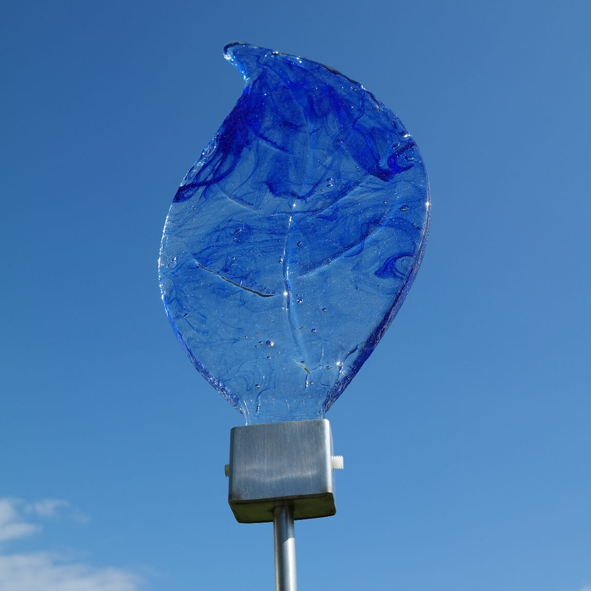 Foglia di vetro blu come decorazione da giardino esclusiva su asta di metallo davanti a cielo azzurro