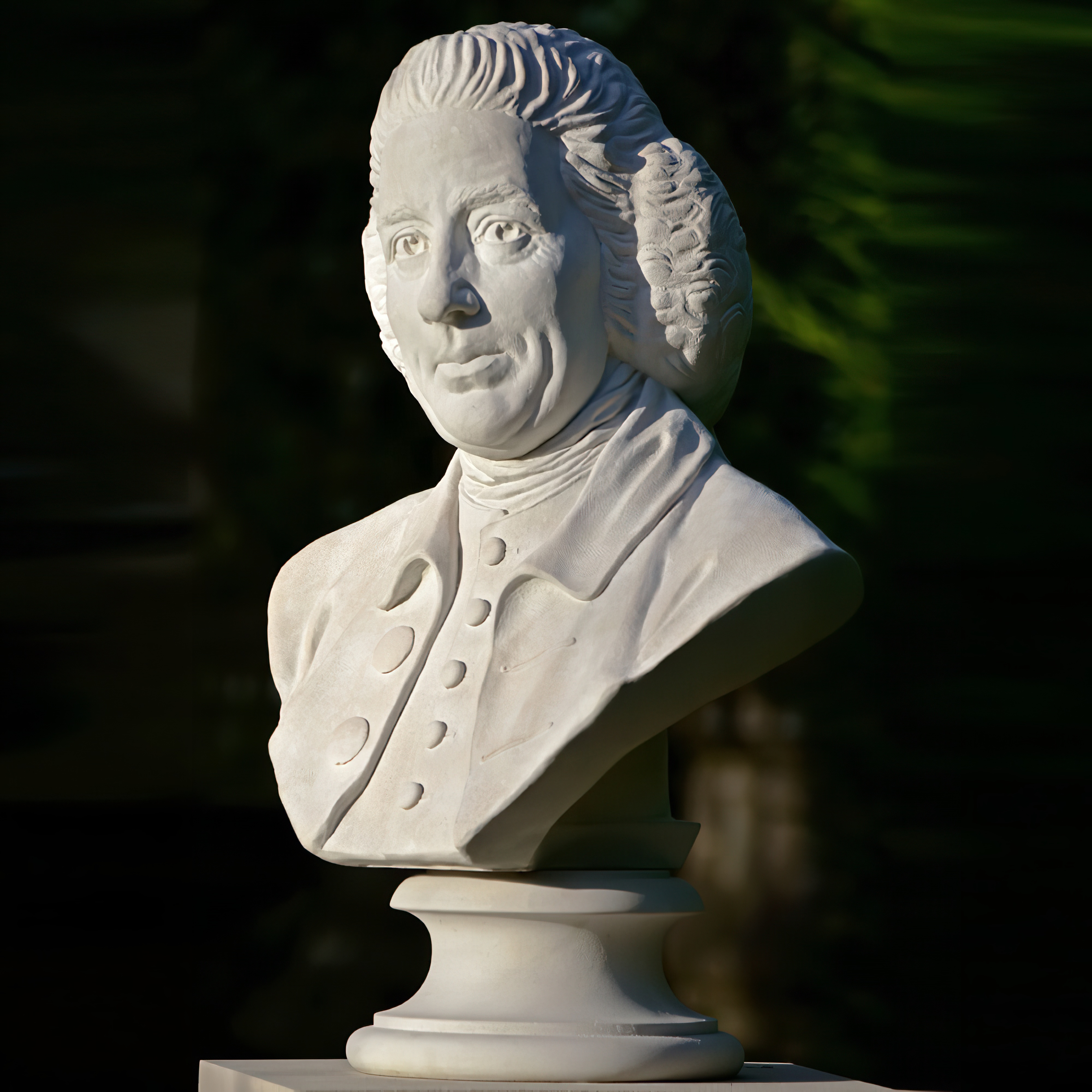 Buste blanc en marbre d'un élégant homme classique dans un jardin avec un fond vert