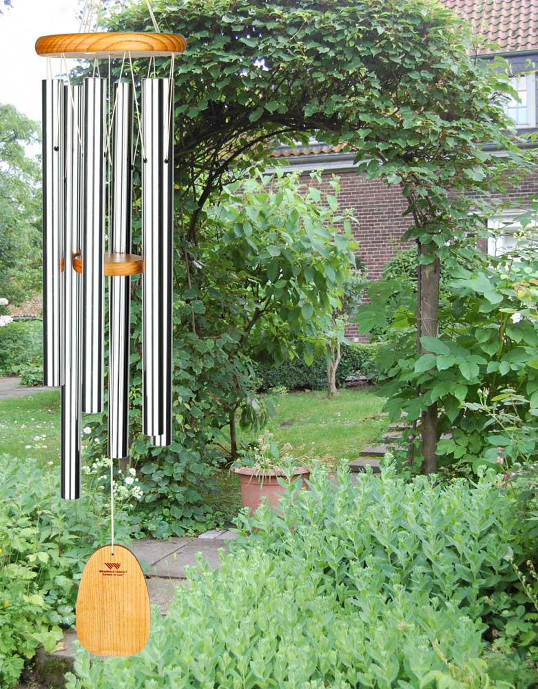 Beau carillon avec longs tubes en métal et suspension en bois dans un jardin verdoyant
