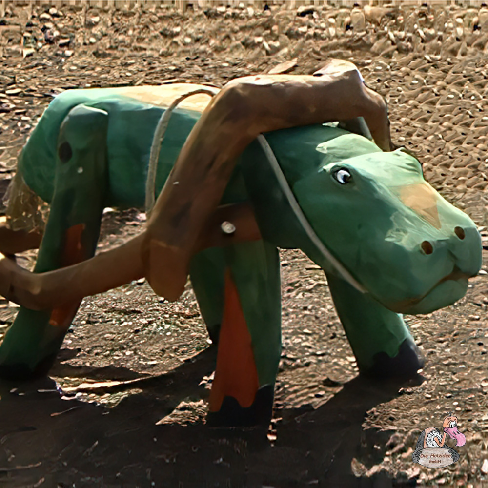 Grüne hölzerne Tierfigur als Gartendeko auf Erde stehend
