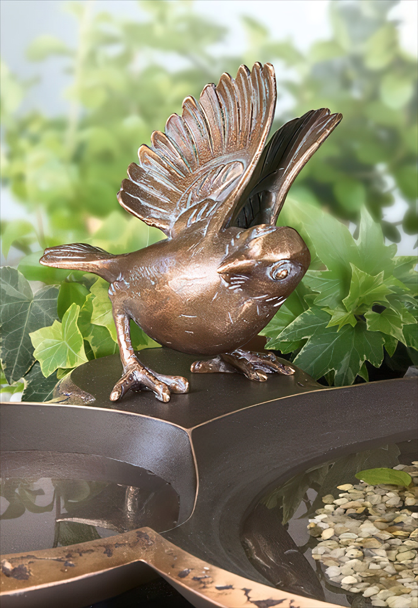 Primo piano di una scultura di uccello in bronzo come decorazione da giardino con fogliame verde sullo sfondo