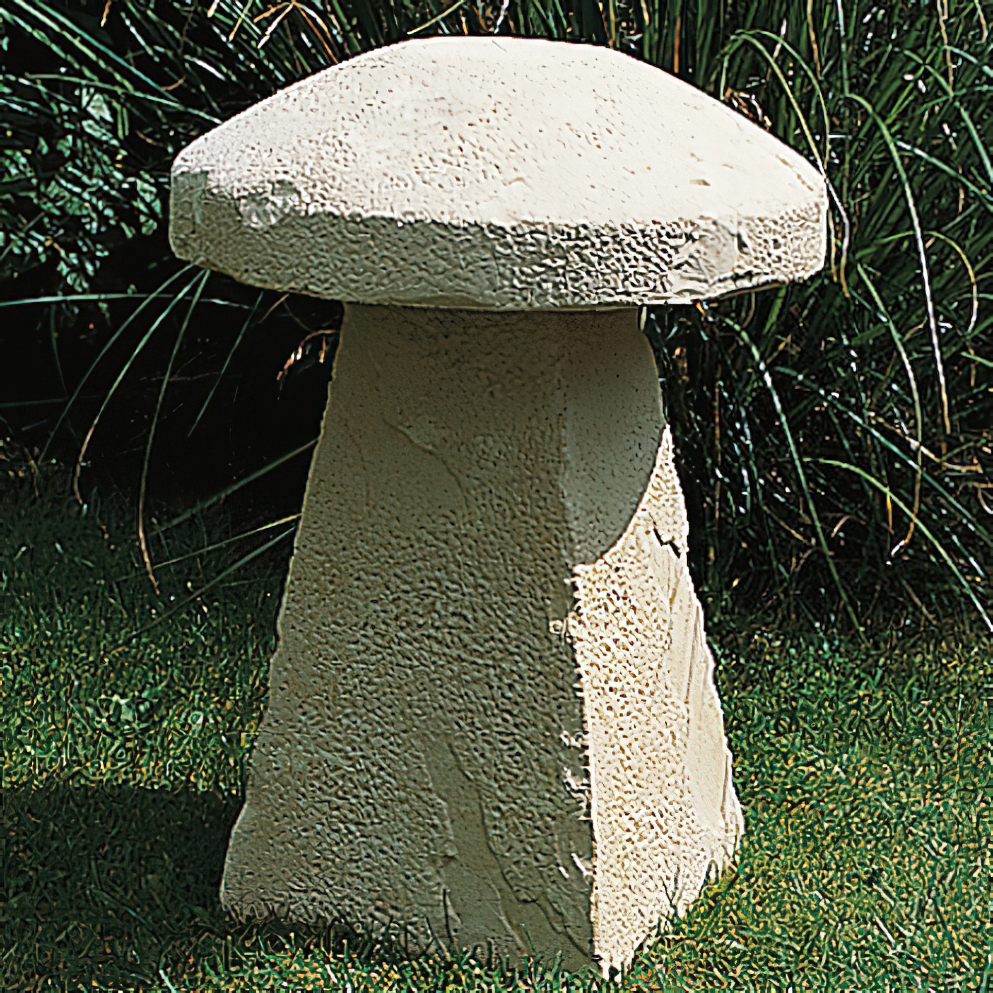 Figurine de champignon beige en pierre décorant un jardin sur de l'herbe verte