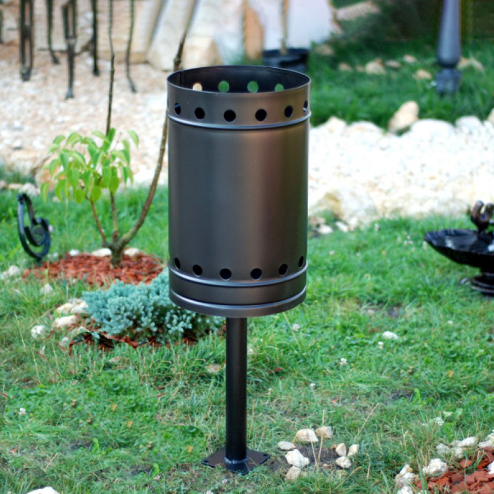 Schwarzer Metall-Abfalleimer mit Löchern, im grünen Garten installiert