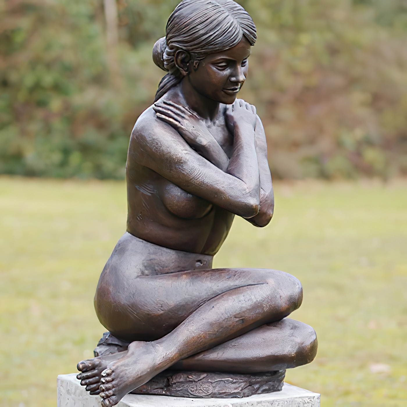 Scultura in bronzo di donna nuda seduta su piedistallo in giardino