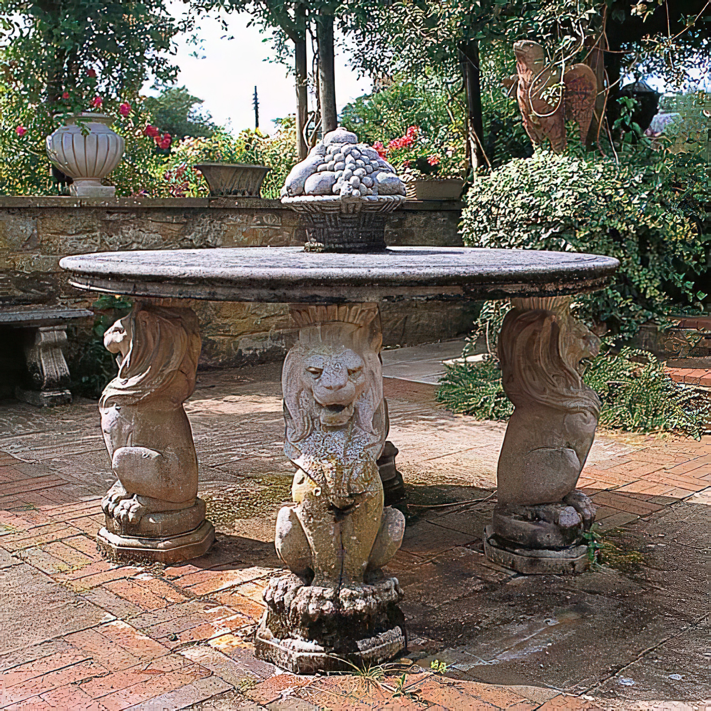 Table ronde en pierre dans un jardin avec trois socles de lions et environnement décoratif
