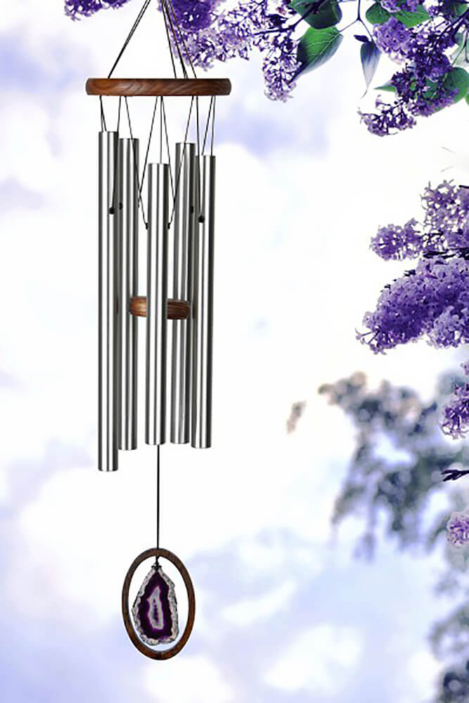 Carillons de jardin argentés avec pendentif en améthyste, entourés de fleurs bleues et ciel bleu